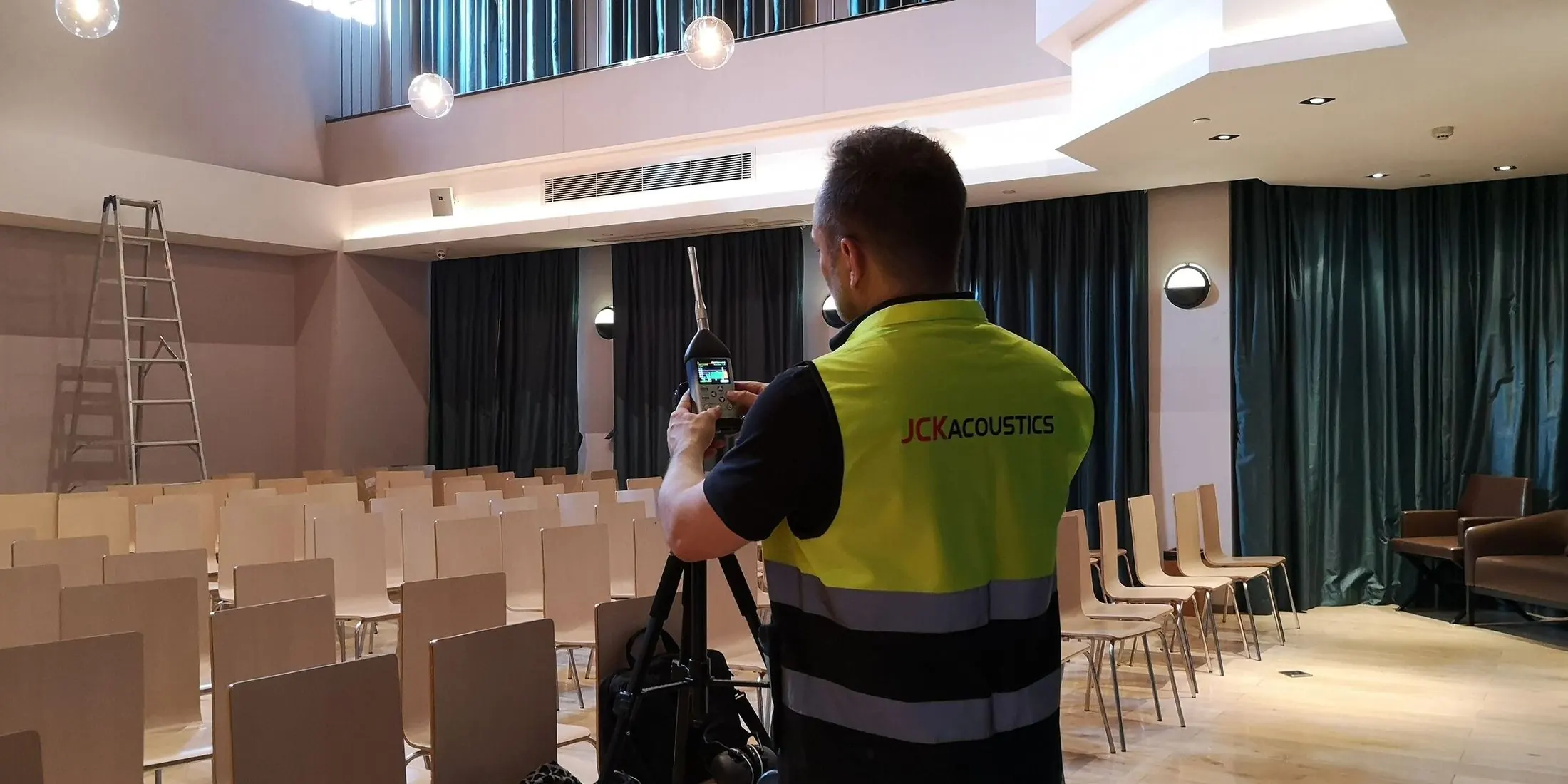 JCK Acoustics engineer measuring room acoustics in an auditorium