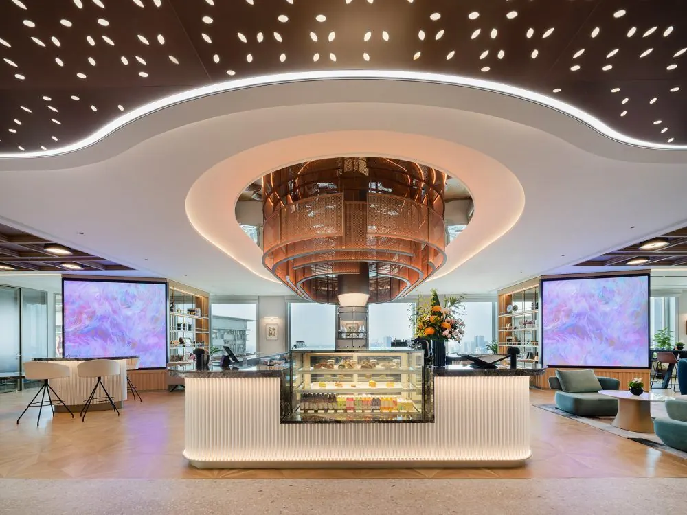 Clubhouse cafe counter under a sculptural chandelier and a perforated wood ceiling